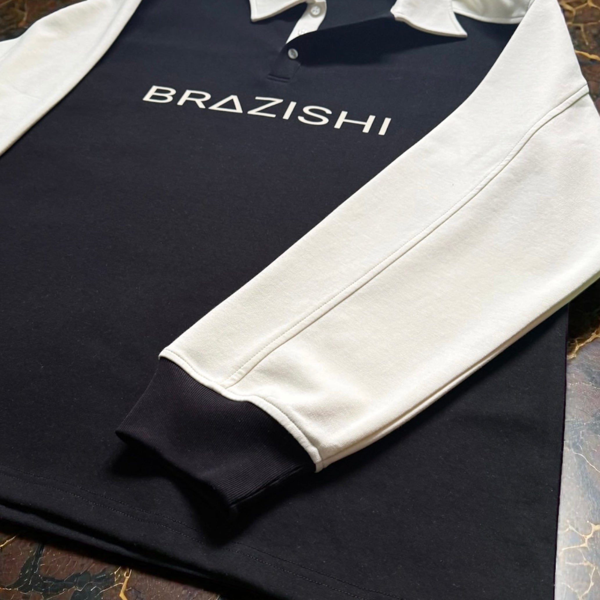 Folded black and ivory shirt with 'BRAZISHI' branding on a marble surface